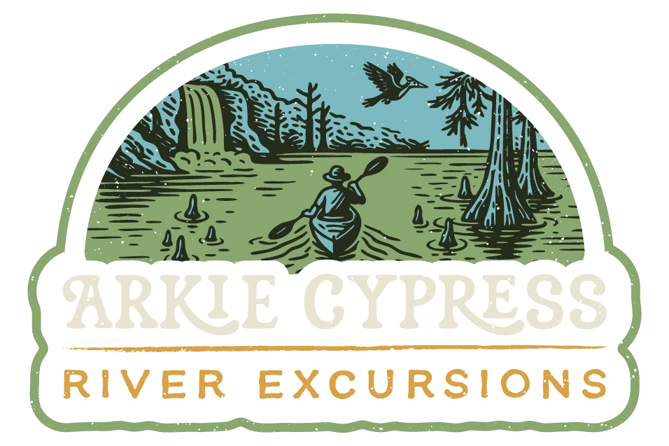 A person paddles a canoe on a river with cypress trees, a waterfall, and a flying bird. Text reads: Arlie Cypress River Excursions.